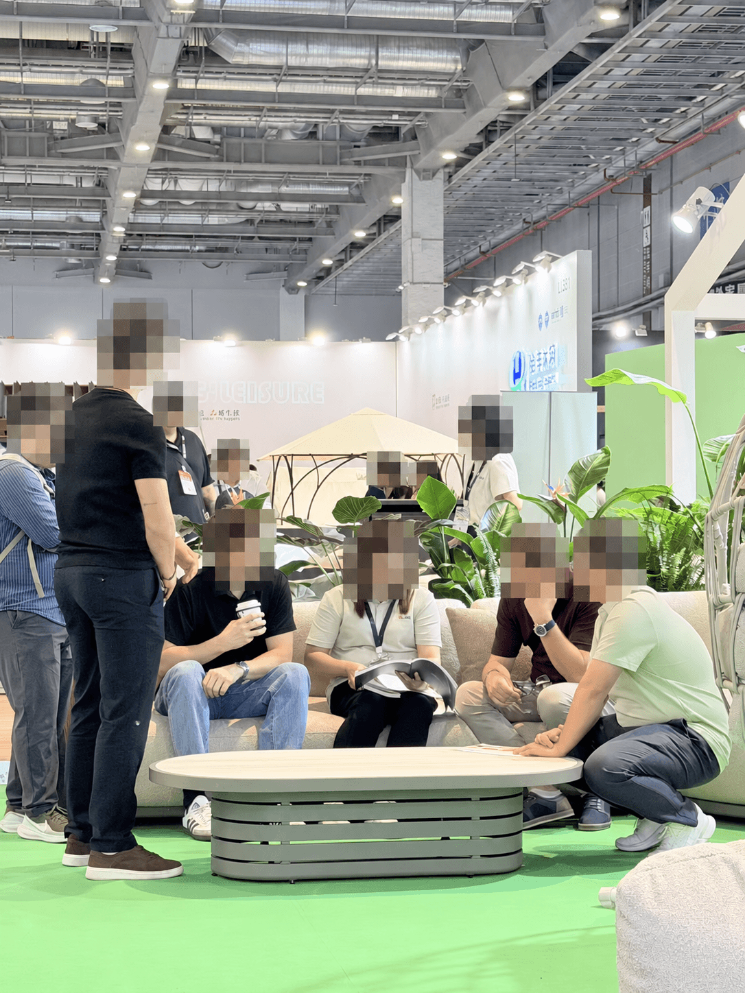 Visitors and the Alomé team discussing furniture at the show, with faces obscured for privacy